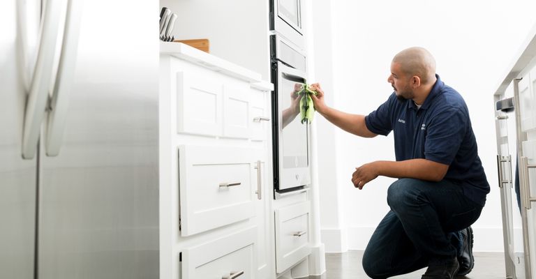 Man cleaning kitchen oven with green towel
