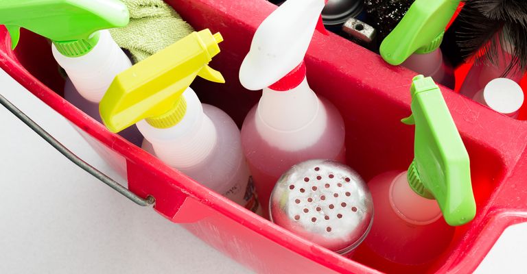Bucket of house cleaning supplies with many spray bottles